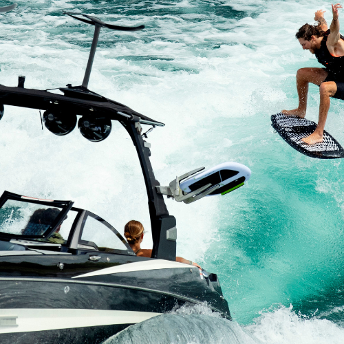 Man riding on a wakesurf board behind a boat